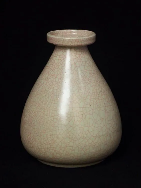 A pale celadon bottle with a narrow neck against a black background