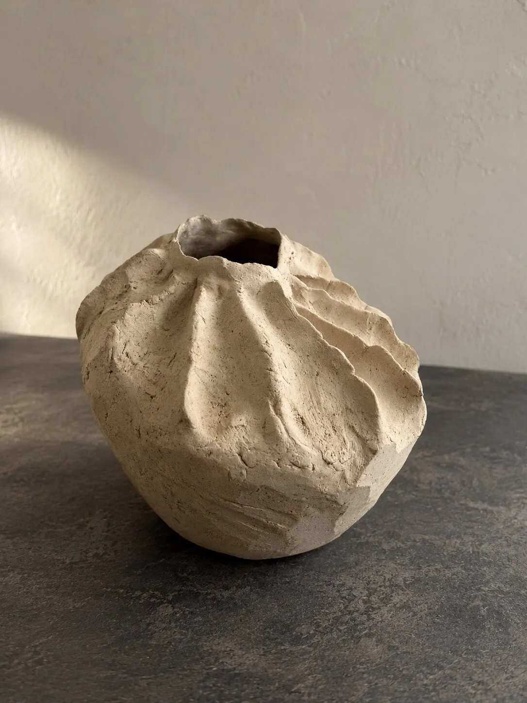 A pale, crumpled-looking vessel with a small opening, like folded paper