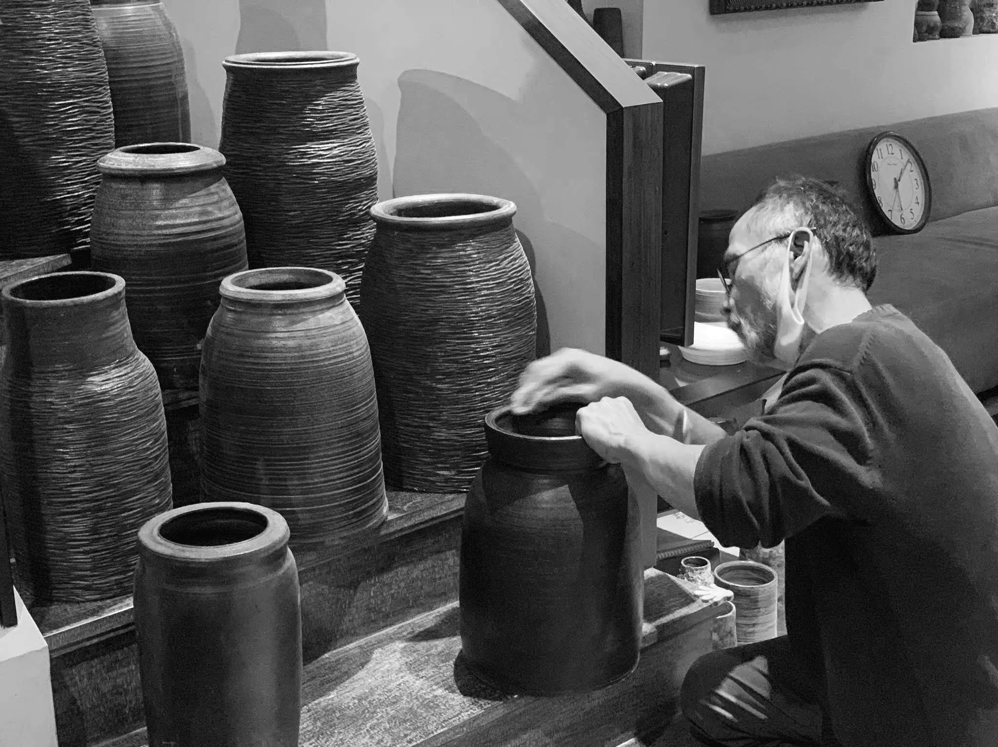 Hải working on a large jar in his studio, surrounded by tall vessels