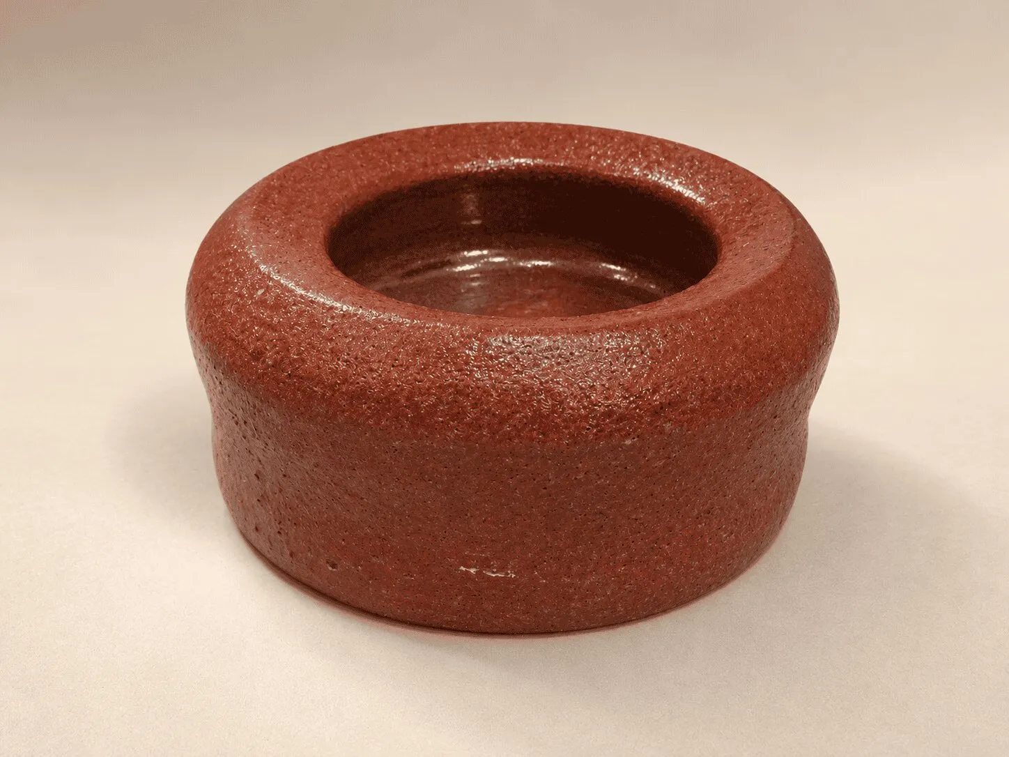 A low, rounded bowl in a deep iron-red glaze