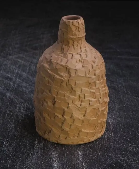 A bottle with a faceted, chiselled ochre surface against a dark backdrop