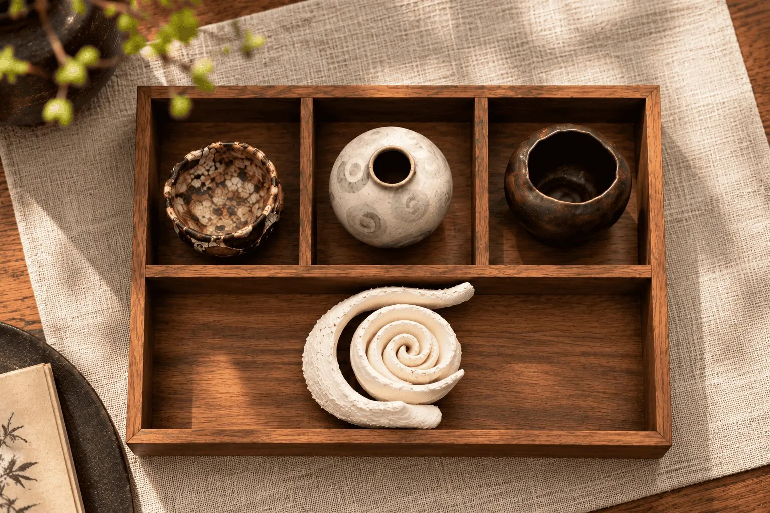 A wooden tray holding small pieces, including a spiral form and miniature bowls