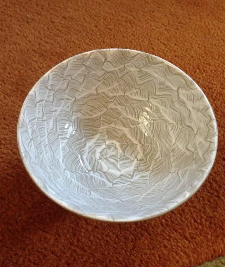 A white crackle-glazed bowl on a terracotta-coloured cloth